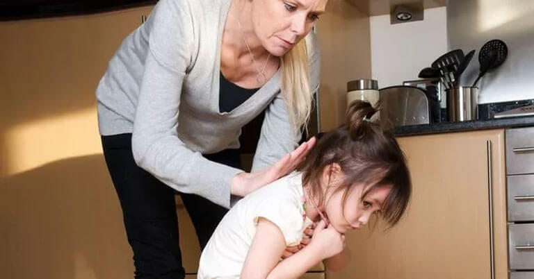 Parent helping a young child in the kitchen
