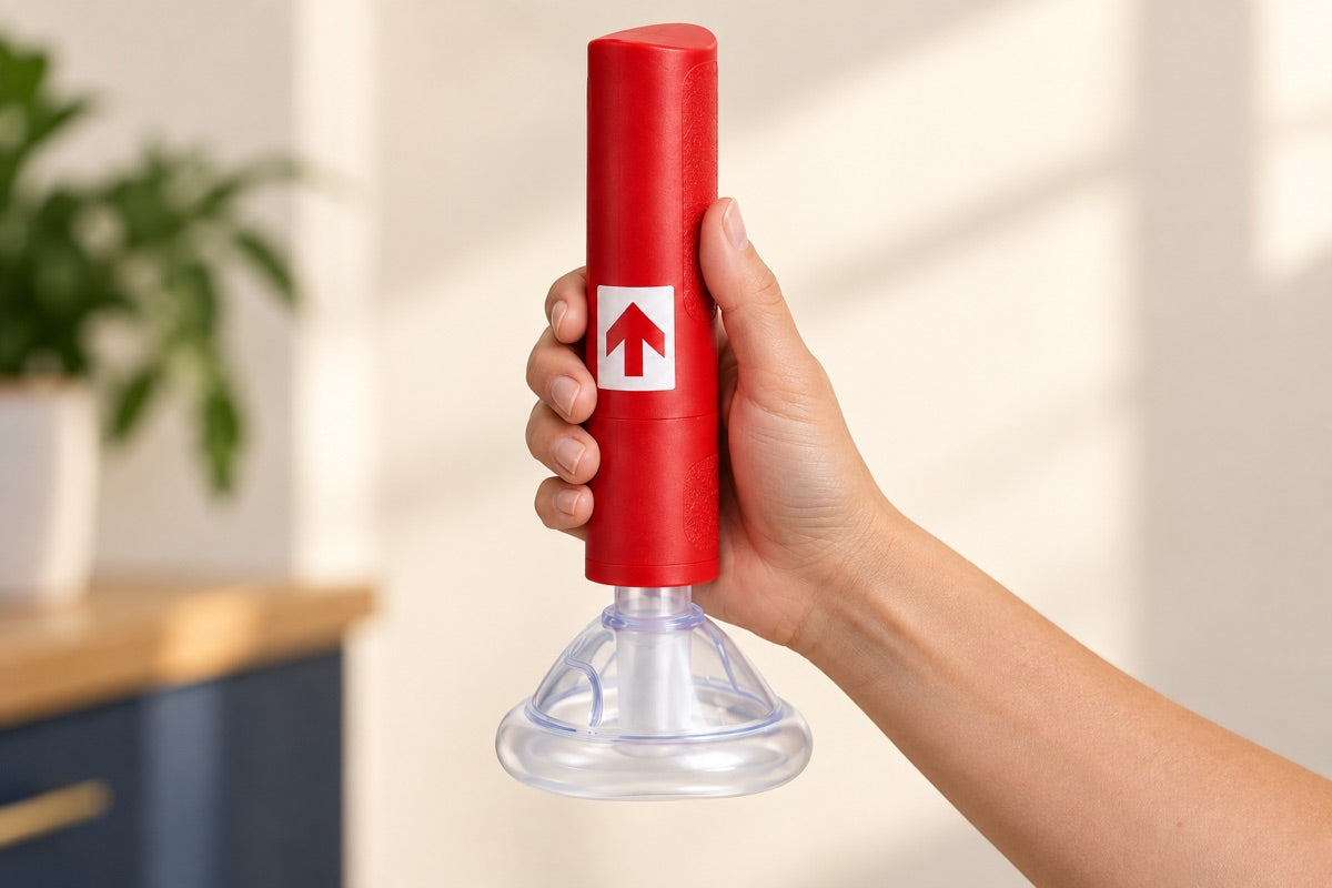 Close-up of the red RescUAid manual handle and clear mask held in one hand; product illustration.